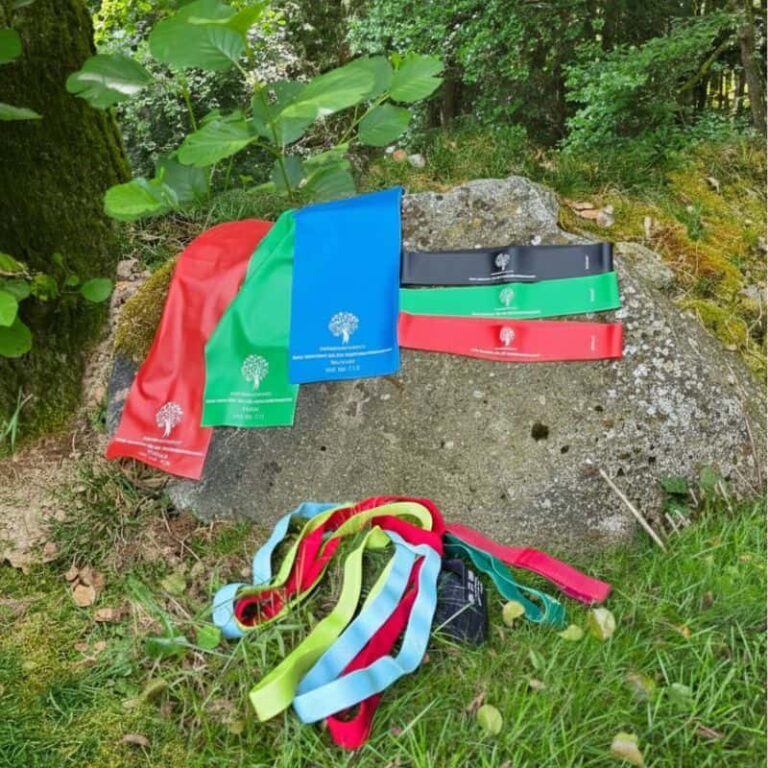 Fitnessbänder in verschiedenen Stärken von HUMANWERKSTATT – Latex- und Textilbänder für Krafttraining, Mobilisation und Physiotherapie, fotografiert in der Natur.